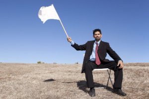 a man holds up a white flag knowing he must surrender to succeed