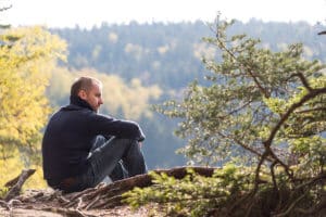 man sits outside in nature looking at trees and thinking about the opioid epidemic by state