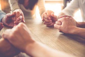 A group of people hold hands while practicing their faith