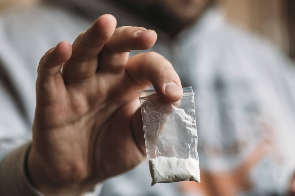man holding out bag of cocaine warning about cocaine overdose symptoms