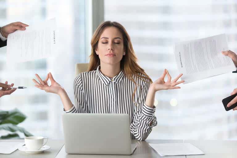 woman at a desk with a laptop doing a yoga pose. how to practice patience