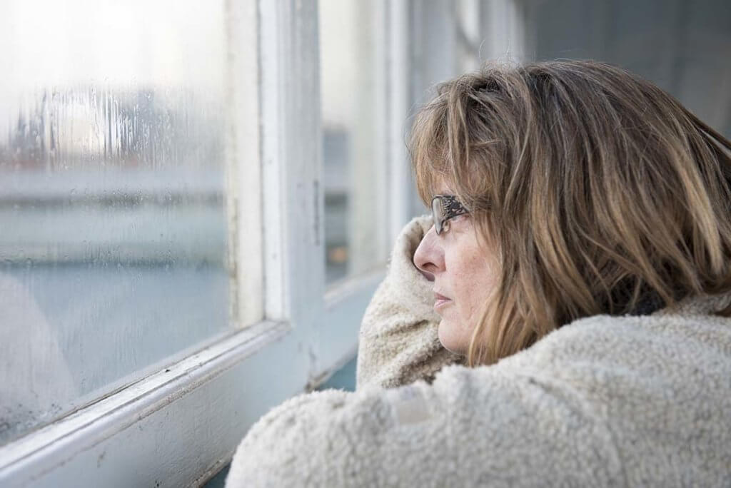 older woman looking pensively out of a rainsoaked window thinking about xanax withdrawal timeline and xanax withdrawal symptoms